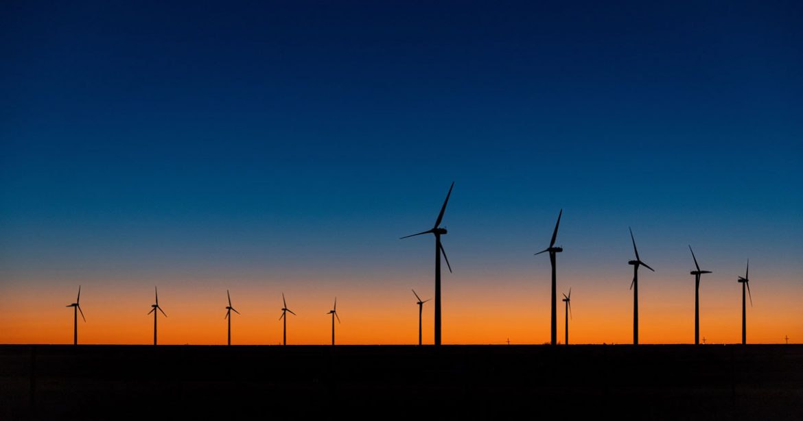 A view of wind turbines against a dramatic sundown sky